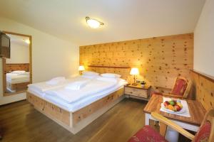 a bedroom with a large bed with a wooden wall at Alpenhotel Tirol in Galtür