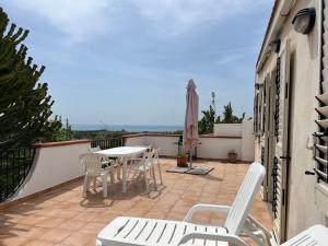 eine Terrasse mit einem Tisch, Stühlen und einem Sonnenschirm in der Unterkunft Pezzino Green Home in Agrigento