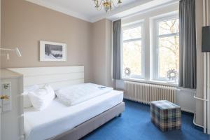 ein Schlafzimmer mit einem weißen Bett und zwei Fenstern in der Unterkunft Hotel Wehrburg in Cuxhaven + 105 Fotos