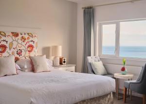 a bedroom with a bed and a window with the ocean at Boskerris Hotel in St Ives