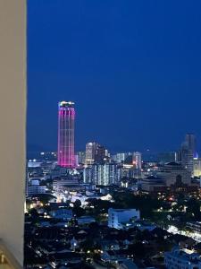 un perfil urbano con un edificio alto con luces rosas en Mansion One l 4pax Studio l Cityview l Gleneagle l by PerfectSweetHome, en George Town