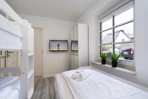 a white bedroom with a bed and a window at Albatros EG in Tinnum