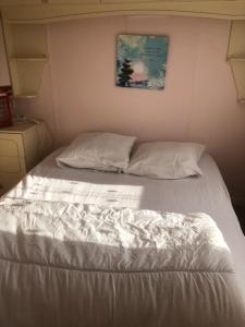 a white bed in a room with a picture on the wall at Mobilhome 4pers avec terrasse in Saint-Martin-aux-Buneaux