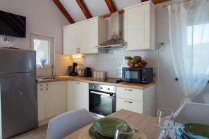 a kitchen with white cabinets and a table with a microwave at Holiday Home Moliva in Donje Sitno