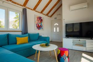 a living room with a blue couch and a tv at Holiday Home Moliva in Donje Sitno