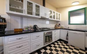 a kitchen with white cabinets and a checkered floor at Pitstop Lodge Guesthouse B&B in Warwick
