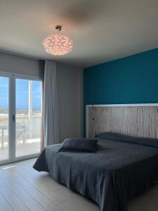 a bedroom with a bed with a blue wall and a window at Tab&ugrave; Hotel in Porto Cesareo