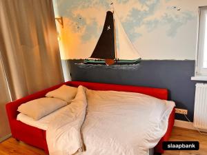 a bed with a painting of a sailboat on the wall at 't Paviljoenhûs bij Sneekermeer in Offingawier