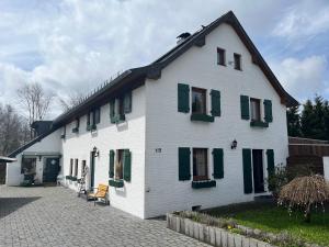 a white house with green shutters and a courtyard at Heckenstübchen in Simmerath