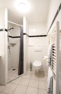a white bathroom with a shower and a toilet at Hotel Old Dutch in Volendam