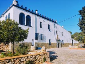 uma casa branca com uma parede de pedra em frente em Masia St Salvador 1582 em Cubelles