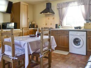 a kitchen with a table and a washing machine at Cefn Helyg Bach - 28453 in Cemaes Bay