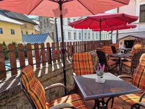 a table and chairs with red umbrellas on a patio at Penzión na Trojice & Reštaurácia FORTUNE in Banská Štiavnica