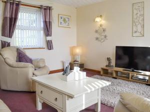 a living room with a white coffee table and a tv at Cefn Helyg Bach - 28453 in Cemaes Bay