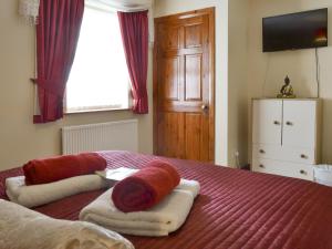 a bedroom with a red bed with towels on it at Cefn Helyg Bach - 28453 in Cemaes Bay