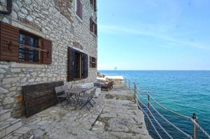 ein Gebäude mit einem Tisch und Stühlen neben dem Wasser in der Unterkunft Chesa Konoba in Rovinj