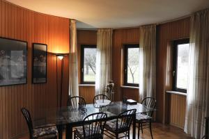 a dining room with a table and chairs and two windows at Aleanna Appartamenti in Nocera Umbra