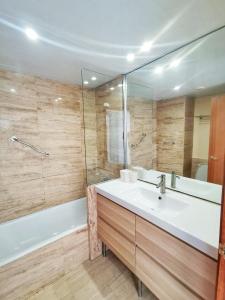 a bathroom with a sink and a tub and a mirror at Seafront apartment in Blanes in Blanes