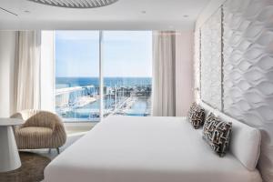 a bedroom with a large white bed and a large window at Hotel Marina Badalona in Badalona