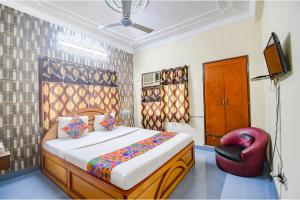 a bedroom with a bed and a red chair at FabHotel Heritage Inn in Kolkata