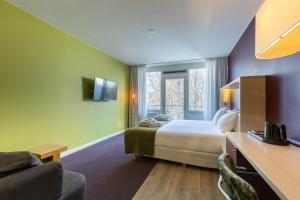 um quarto de hotel com uma cama e uma televisão em Amrâth Airport Hotel Rotterdam, BW Signature Collection em Roterdão
