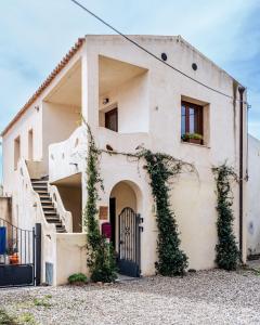 una casa bianca con cancello e scale di Domo Mea Terra e Domo Mea Chelu - Comfort nel centro storico di Orosei a Orosei