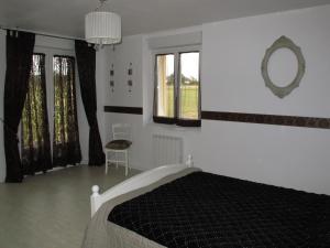 La Vigneraie de Meusnes في Meusnes: غرفة نوم مع سرير ومرآة على الحائط
