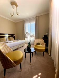 a bedroom with a bed and two chairs and a table at Hotel Carlton in Beaulieu-sur-Mer