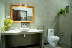 W łazience znajduje się umywalka, toaleta i lustro. w obiekcie Tectona Grandis - Negombo w mieście Gampaha