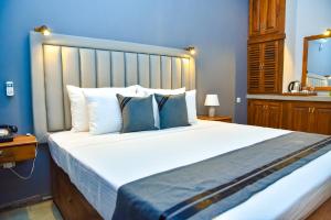 een slaapkamer met een groot wit bed met blauwe muren bij Tectona Grandis - Negombo in Gampaha