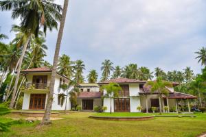 an exterior view of a house with palm trees at Tectona Grandis - Negombo in Gampaha