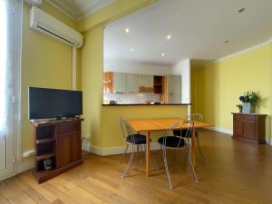 a dining room with a table with chairs and a television at Grosso 4 Pers WiFi AC Parking in Nice