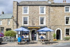 a brick building with blue umbrellas in front of it at Burn Cottage in Leyburn