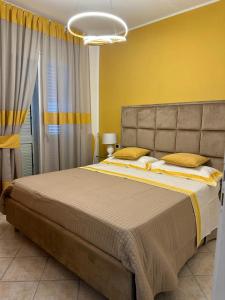 1 dormitorio con 1 cama grande y pared amarilla en Exclusive apartment Piccola Marina, en Isquia