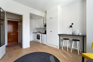 a kitchen with white cabinets and a counter and stools at Forenom Serviced Apartments Helsinki Kruununhaka in Helsinki