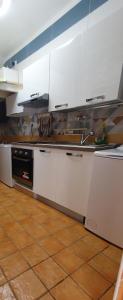 uma cozinha com armários brancos e piso em azulejo em CASA VACANZE DI MARILENA em Vietri