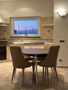 una mesa y sillas en una cocina con ventana en Exclusive apartment Piccola Marina en Ischia