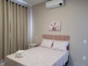 una camera con un letto con una coperta rosa e bianca di Flats Ipê a Pirenópolis