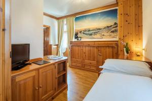 - une chambre avec un lit et une télévision sur une armoire en bois dans l'établissement Franceschi Park Hotel, à Cortina dʼAmpezzo