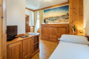 a bedroom with a bed and a tv on a wooden cabinet at Franceschi Park Hotel in Cortina dʼAmpezzo