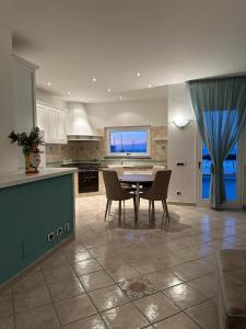 Exclusive apartment Piccola Marina في ايسكيا: مطبخ وغرفة طعام مع طاولة وكراسي