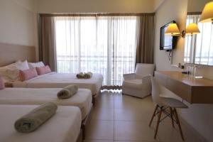 a hotel room with two beds and a desk at Sandy Beach Hotel & Spa - ex Sentido in Larnaca