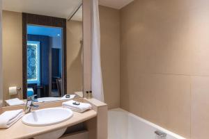 ein Badezimmer mit einem Waschbecken, einer Badewanne und einem Spiegel in der Unterkunft Central Hotel Paris in Paris