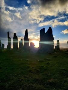 a group of stonehenge formations in a field with the sunset at Dunan Hotel in Breasclete