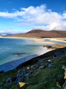 a beach with rocks and the ocean and mountains at Dunan Hotel in Breasclete