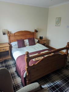 Un dormitorio con una gran cama de madera con almohadas moradas en Doune Braes Hotel, en Breasclete