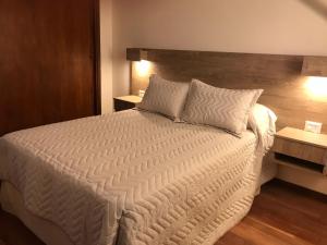 a bedroom with a large white bed with two tables at Chacabuco Centro Apartment in Tandil