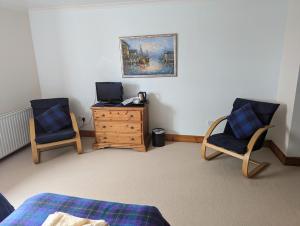 a bedroom with two chairs and a tv and a dresser at Doune Braes Hotel in Breasclete