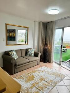 a living room with a couch and a large window at Bali in Blouberg in Cape Town