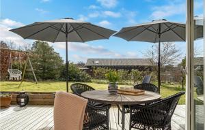 un patio con una mesa y sillas con sombrillas en Nice Home In Dronningmlle With Kitchen, en Dronningmølle